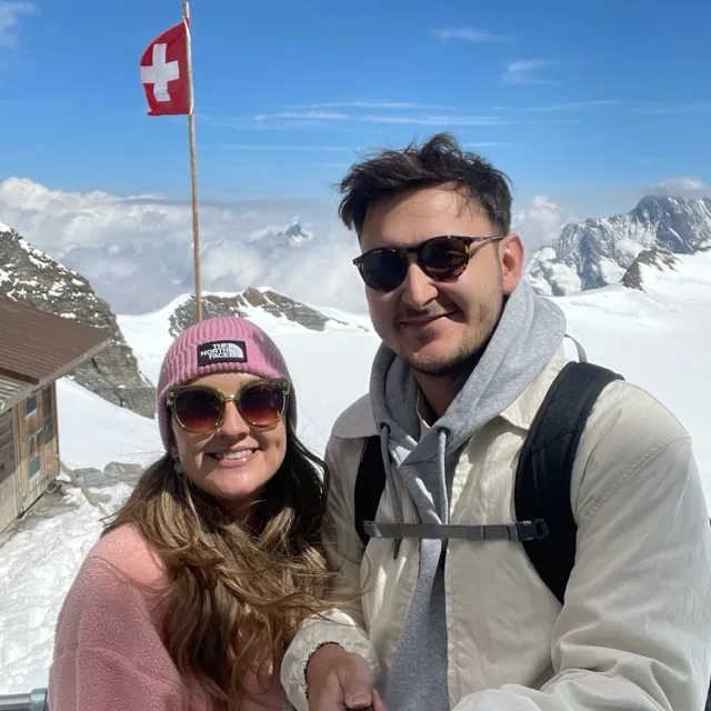 Benjamin and Danielle in the snow beside a Swiss flag